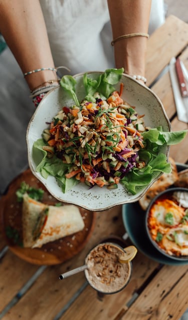 a person holding a plate with a salad on it