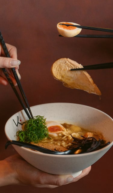 a person holding chopsticks in a bowl of soup