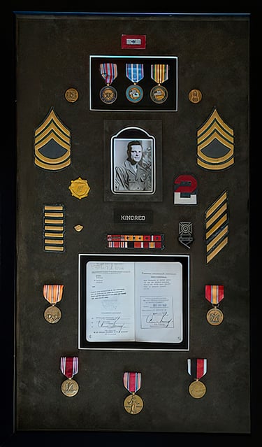 Military shadow box display with service medals, sergeant rank insignia, and a vintage soldier portrait.