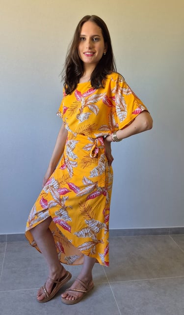 Mulher em pé usando uma saia envelope amarela, com estampa de folhas.