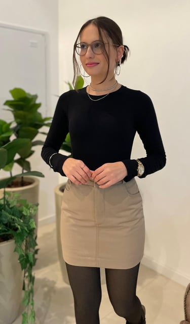 Mulher vestindo saia curta de sarja bege com bolsos frontais e blusa preta de manga longa.