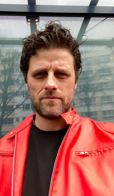 Rob Phillimore PR Consultant in Berlin, Germany wearing a red jacket and black t-shirt