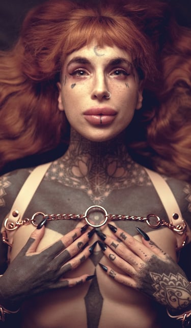 a woman with ginger hair with tattoos on her chest and wearing a harness