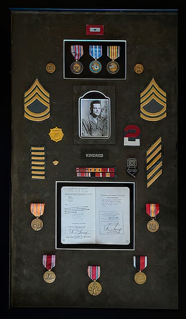 Military shadow box display with service medals, sergeant rank insignia, and a vintage soldier portrait.