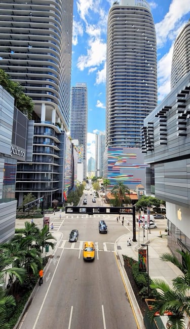Una bulliciosa calle de la ciudad de Brickell, Miami, con modernos rascacielos y tráfico urbano.