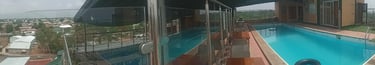 a person standing on a glass wall with a pool in the background