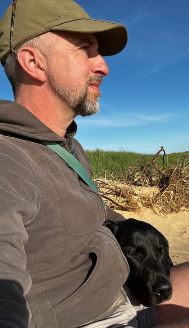 a man sitting on a beach with a dog