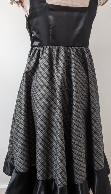 The back of a black/gold plaid and black satin flowy cocktail dress