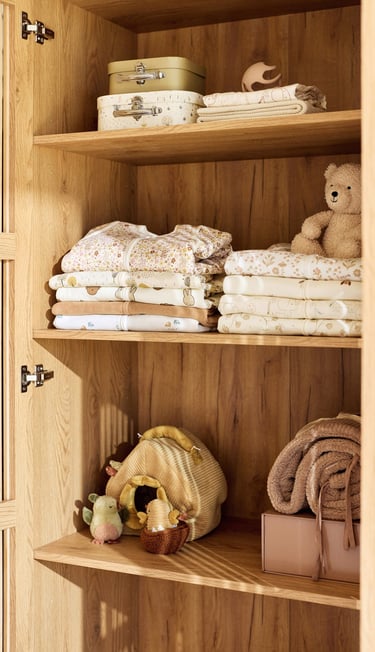 Photo of cupboard shelves with Jollein sleepsuits and toys