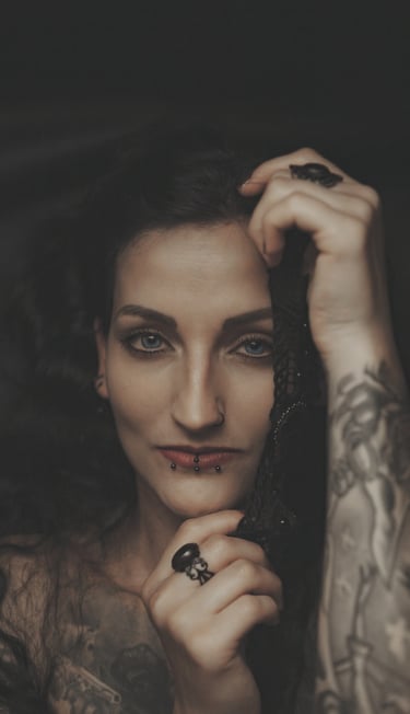 portrait of a woman with tattoos on her arm looking at the camera