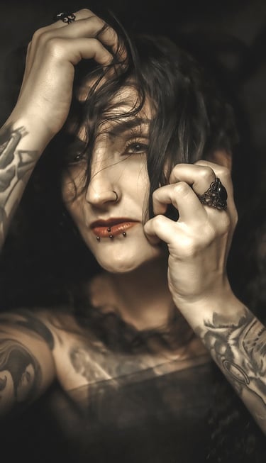 Portrait of a woman with tattoos on her arm and a on her chest, holding her head
