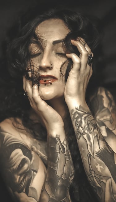 Portrait of a woman with tattoos on her arm and a on her chest, holding her head