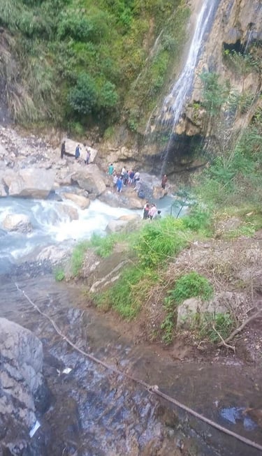 Umbrella waterfall in a valley with people standing around