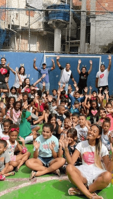 Voluntários e assistidos da ONG Eu Ajudo Como Dá, durante evento em quadra de comunidade