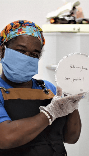 Voluntária da ONG Misturaí segurando uma das marmitas produzidas e distribuidas a população carente 