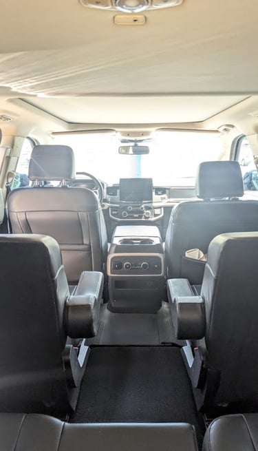 Interior view of a modern SUV with black leather captain's chairs and a spacious panoramic sunroof.