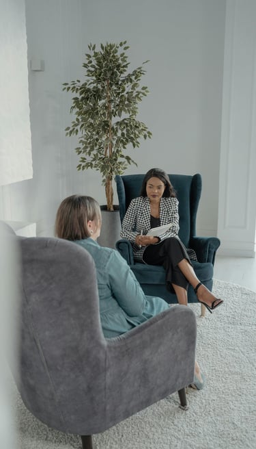 two ladies sitting on armchairs with one lady providing coaching to the other
