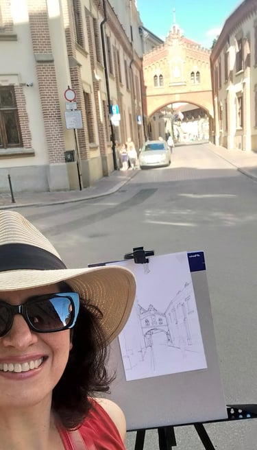 Mag Wilk ( Magdalena Wilk-Dyszkiewicz) in a hat and sunglasses is holding a drawing of a house