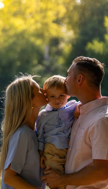 Familienshooting Coburg: Glücklicher Moment, Eltern geben ihrem Sohn einen Kuss auf die Wange.