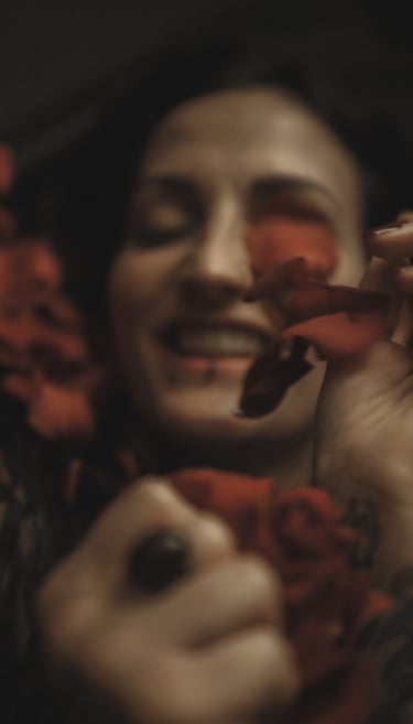 a woman with tattoos on her arms and rose petals, she is smiling