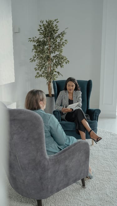 two ladies sitting on armchairs with one lady providing coaching to the other