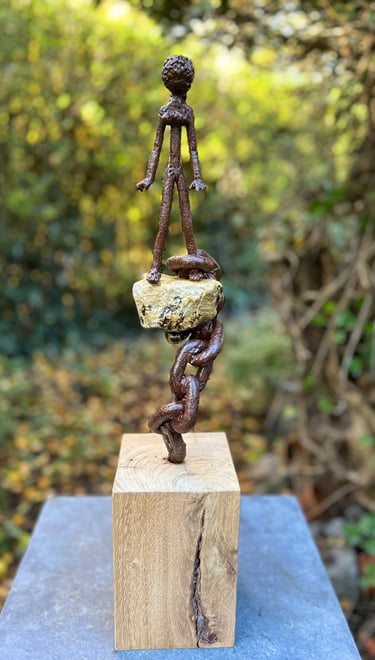 Iron sculpture with stone on wooden pedestal