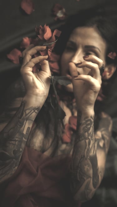 a woman with tattoos on her arms and rose petals