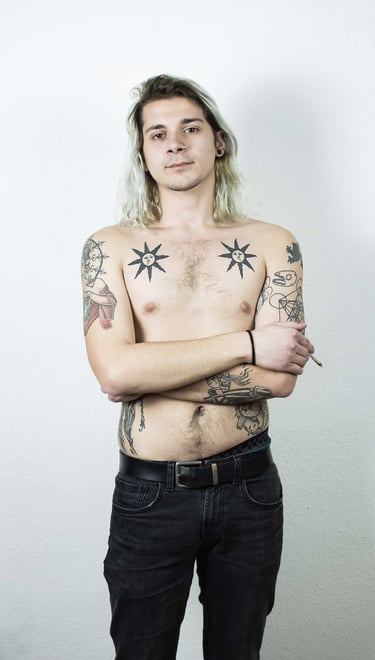 a man with tattoos on his chest posing for a photo