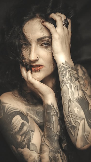 Portrait of a woman with tattoos on her arm and a on her chest, holding her head