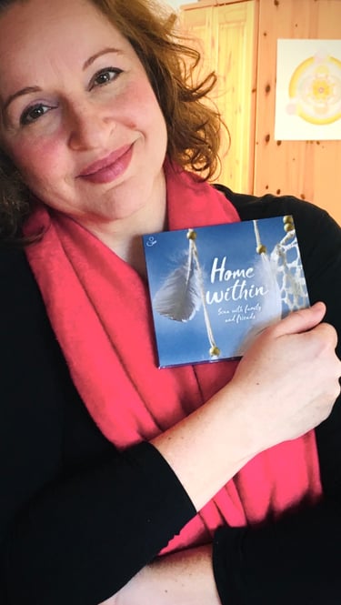 eine Frau lehnt am Türrahmen und hält eine CD im Arm, die den Titel "Home Within" trägt.