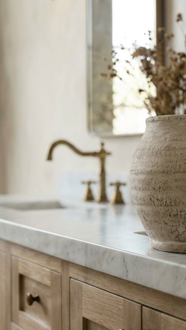 Rustic stone vase on a white marble countertop with wood cabinets and gold bathroom fixtures.