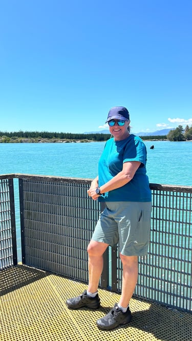 a woman standing on a bridge over looking at the water
