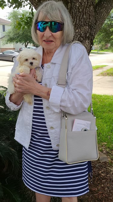 White Maltese Puppy with lady stangding under tree.
