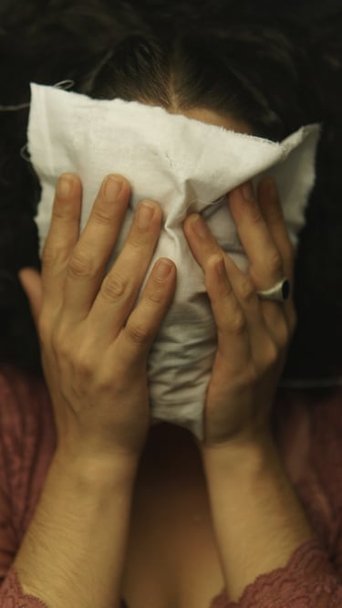 a woman covering her face with a pieace of white fabric
