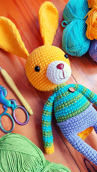 Amigurumi de un conejo amarillo con una camisa a rayas