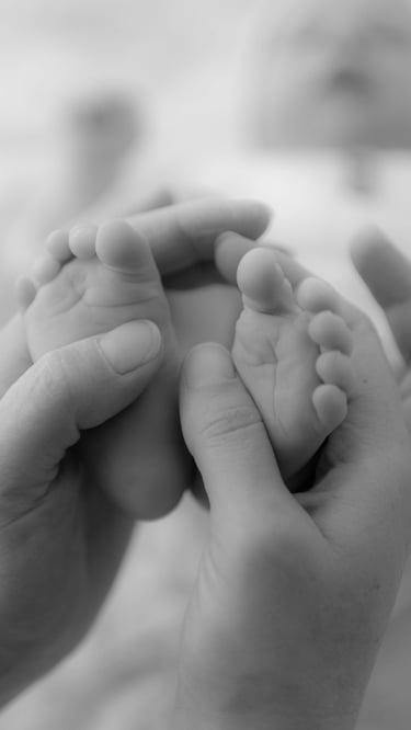Photo en noir et blanc des pieds de bébé entourés de mains réconfortantes