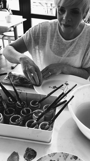 the artist creating with paints and paint brushes and big bowl of water