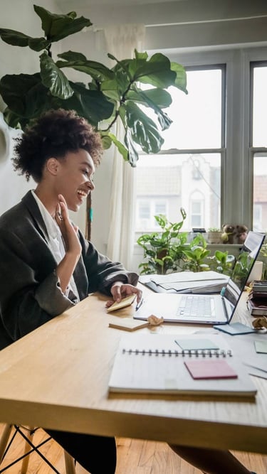 a woman sitting at a desk with a laptop and a notebook