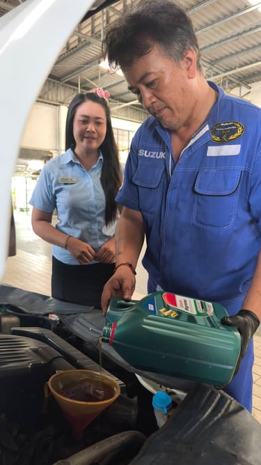 A Suzuki mechanic pouring Castrol Magnatec motor oil into a car engine during a service.