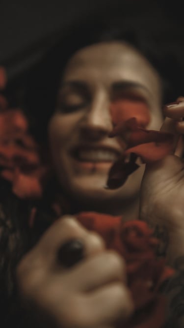 a woman with tattoos on her arms and rose petals, she is smiling