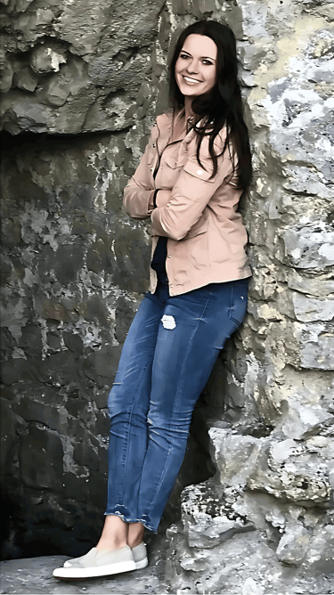 a woman standing in front of a stone wall