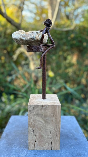 Iron sculpture with stone on wooden pedestal