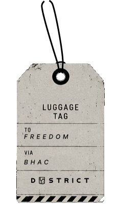 Vintage luggage tag with text 'To Freedom Via BHAC' and Dystrict logo on a dark background.