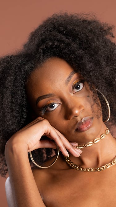 a woman with a large afro - like hair and a gold chain link bracelet