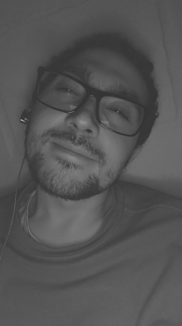 Un primer plano en blanco y negro de un hombre sonriente que lleva gafas.