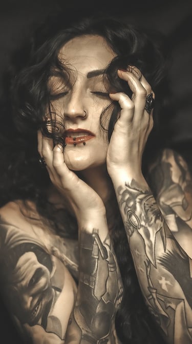 Portrait of a woman with tattoos on her arm and a on her chest, holding her head