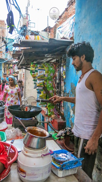 Man cooking outside Delhi slum home