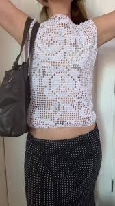 a woman in a white crochet top and black pants