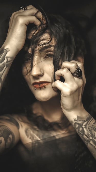 Portrait of a woman with tattoos on her arm and a on her chest, holding her head