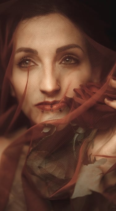 photo of a woman in a red dress with a veil on her head holding a rose